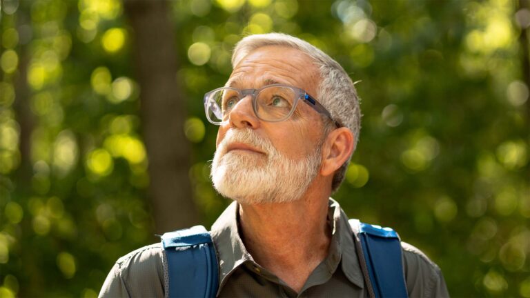 John hiking, looking upwards in forest.