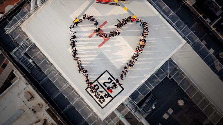 Overhead healthcare professionals forming a heart shape on Cooper hospital's helipad.