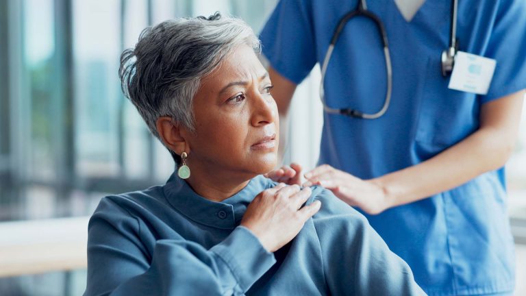 Concerned woman sitting with nurse in chair.