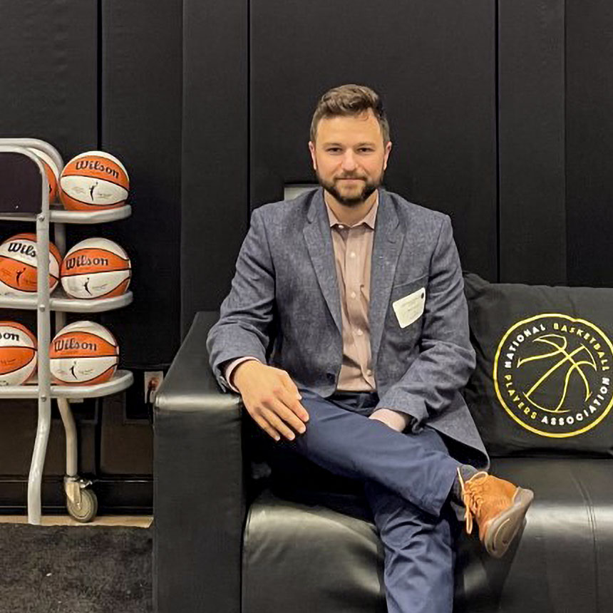 Dr. Caruso sitting with basketballs on rack next to him.