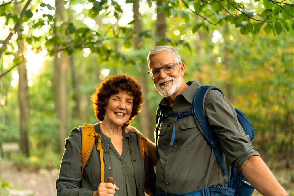 Wendy and John hiking in a sunlit forest.