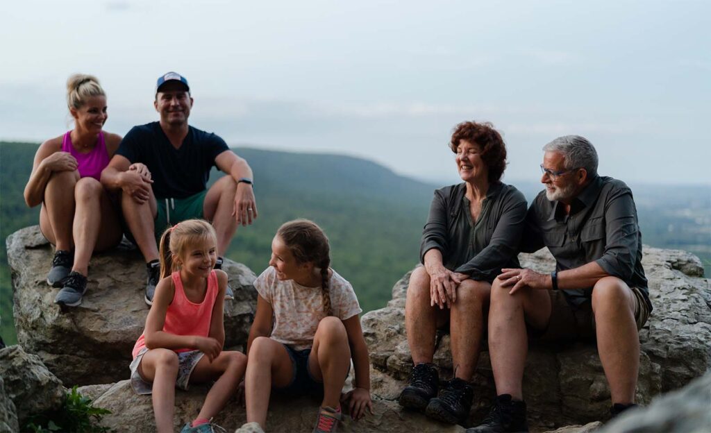 Wendy and her family relaxing on rocks during hike.