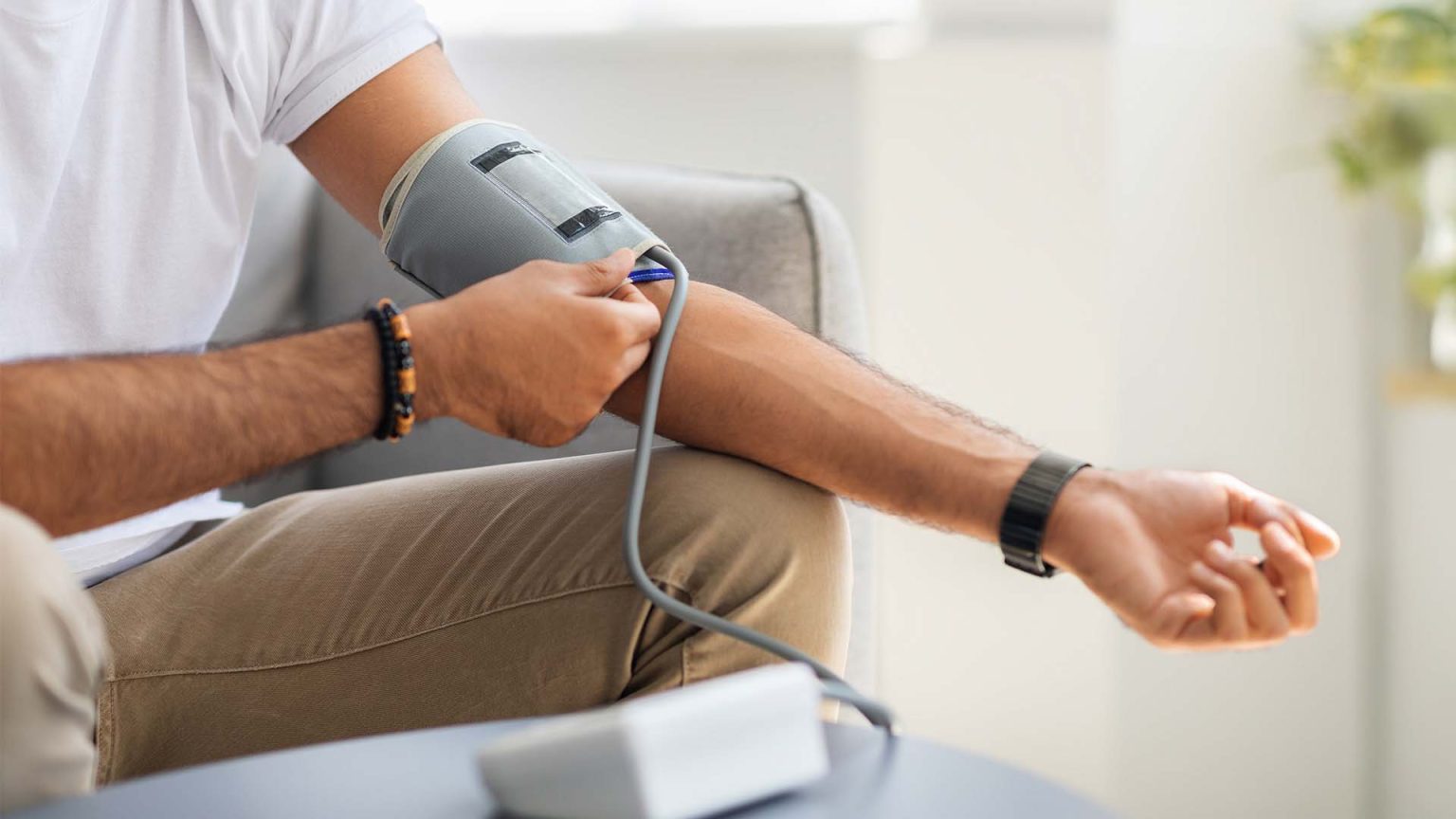 Man using a blood pressure monitor at home.