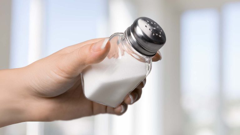 Hand holding a salt shaker.