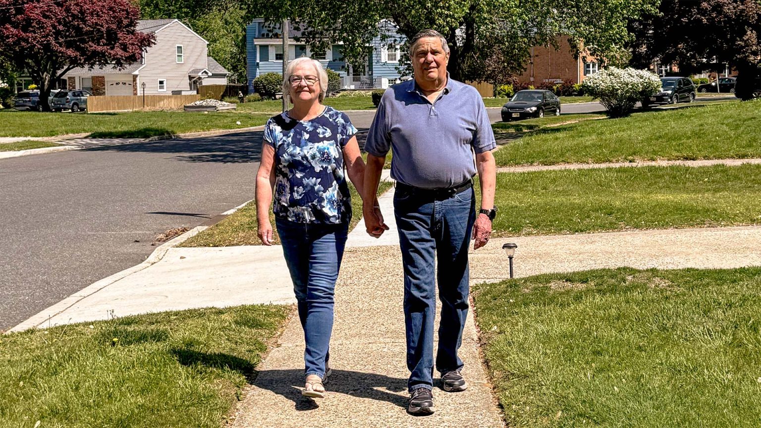 Vince and his wife walking on a sunny suburban street.