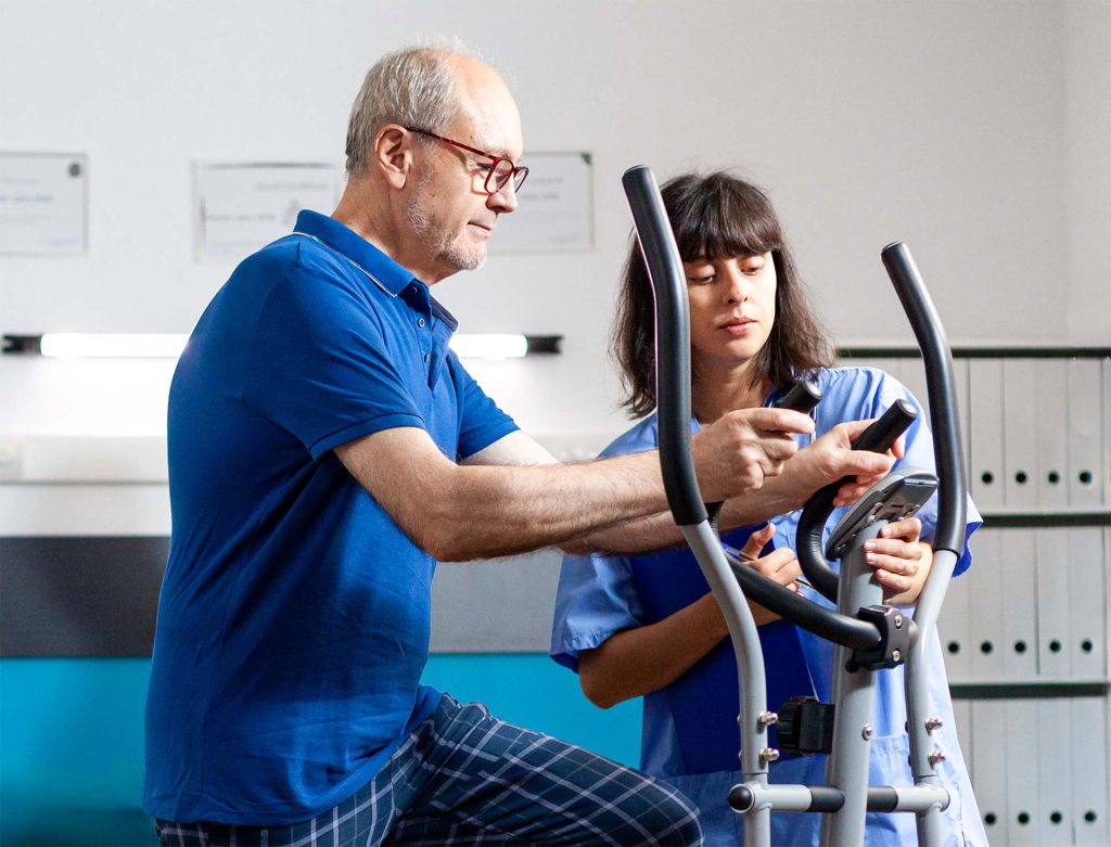 Man and nurse with exercise machine for cardiac rehab.