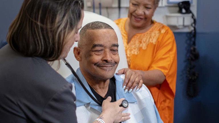 A healthcare professional examines Ward while his wife stands nearby.